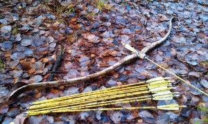 Модерен лък и стрели лежат на земята Снимка: Модерен лък и стрели, лежащи на земята.