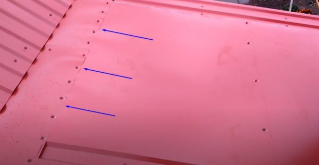 Снимка на ръба на плосък покривен лист, поставен под уламката отстрани на гредата на билото на покрива