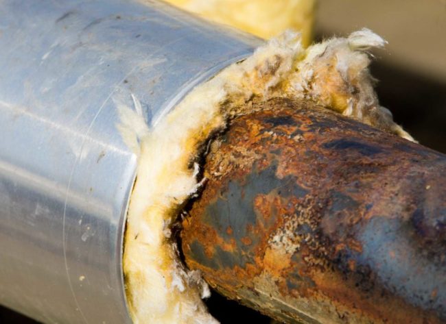 Снимка: Повредена от ръжда тръба под изолация от минерална вата, облицована с фолио