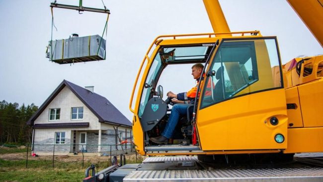 Автокран монтира котелно оборудване по време на монтажа на отоплителна система за дома.